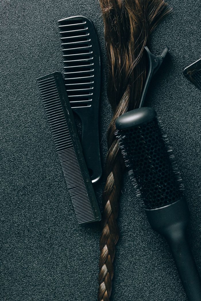 Strona Główna A flat lay of hairdressing tools and a braid on a textured surface, ideal for salons.